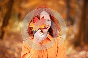 A bright girl with copper-colored hair. Beautiful autumn nature.