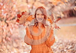 A bright girl with copper-colored hair. Beautiful autumn nature.