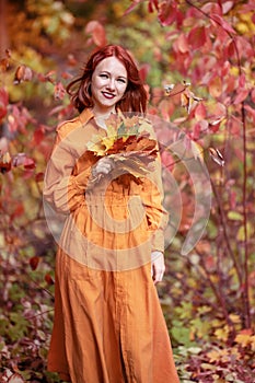 A bright girl with copper-colored hair. Beautiful autumn nature.