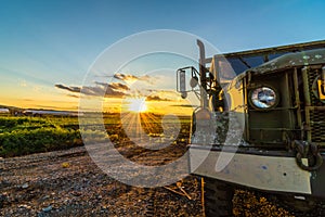 Bright gold sunset shines on heavy duty trucks and farmlands