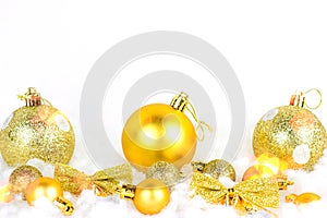 Bright golden Xmas decorations ribbons, baubles, ornament on white snow background with copy space. Christmas and New Year