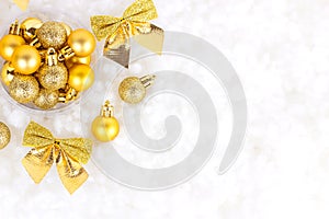 Bright golden and yellow Christmas decorations ribbons, baubles, ornament flat lay on white artificial snow background with copy