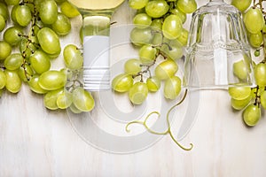 Bright grapes with a bottle of white wine and glass on rustic a white wooden background