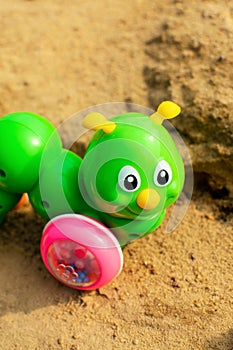 Bright green caterpillar toy in the sandbox.