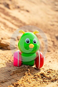 Bright green caterpillar toy in the sandbox.