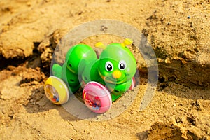 Bright green caterpillar toy in the sandbox.