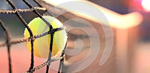 Bright greenish yellow tennis ball hitting the net