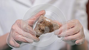 Bright grey ruby crystal ore in hands with gloves. Crystallization is the natural or artificial process by which a solid