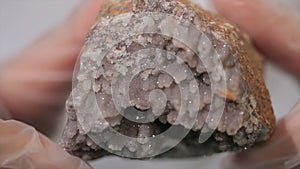 Bright grey ruby crystal ore in hands with gloves. Crystallization is the natural or artificial process by which a solid