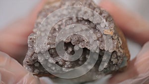 Bright grey ruby crystal ore in hands with gloves. Crystallization is the natural or artificial process by which a solid