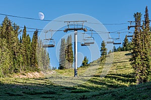 Bright half moon over Sunshine Village chairlift in the summer