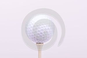 A bright, high-key portrait of a golf ball on a tee.