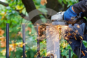 Bright, hot sparks fly out from under the protective cover of the angle grinder when cutting metal