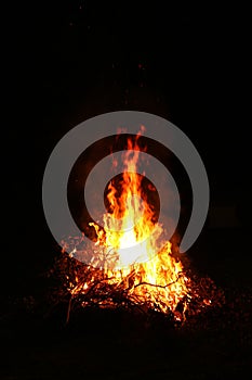 Bright huge flame in the darkness of nature. Summer bonfire at the campsite on a dark night