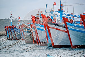 Bright hulls of wooden fishing boats in a row, anchored in the harbor