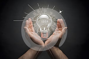 Bright idea depicted by shining lightbulb cradled in human palms, concept of innovation