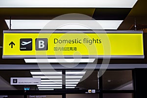 Bright illuminated yellow and black airport signs with arrows and plane icons and the title in Chinese: Domestic flights.