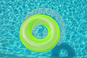 Bright inflatable ring floating in swimming pool, above view