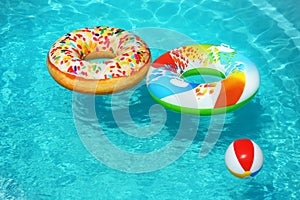 Bright inflatable  and beach ball floating in swimming pool on sunny day. Space for text