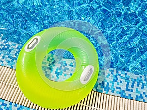 Bright inflatable tube ring floating on blue water surface, in swimming pool during sunny day.bright clear pool water