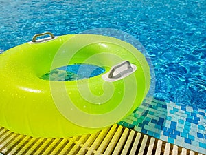 Bright inflatable tube ring floating on blue water surface, in swimming pool during sunny day.bright clear pool water