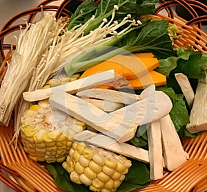 Bright and juicy corn, lettuce, mushrooms cut into slices and stripes in a wicker plate