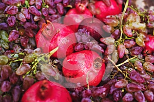 Bright juicy ripe pomegranates, pink grapes, red apples in a clay bowl close-up. Autumn fruit decor