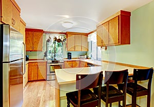 Bright kitchen with light brown cabinets and old wooden stools.