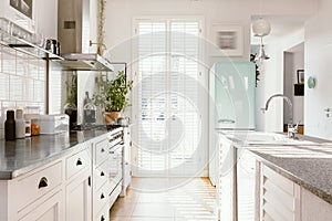 Bright kitchen with modern white furniture, pastel mint fridge and big floor to ceiling window