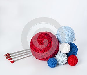 Bright knitting balls and knitting needles on a white background. There is a place for text nearby