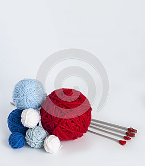 Bright knitting balls and metal knitting needles on white background. There is a place for text nearby