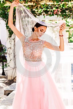 Bright lady bride in a pink wedding dress in tropical garden alley. Wedding day photo session, the main day