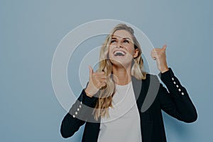 Bright laughing young woman showing thumbs up gesture with both hands