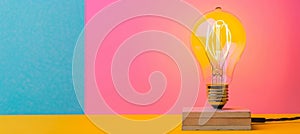Bright light bulb on block with space for customized text against a solid colored background photo