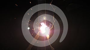 Bright light and sparks from welding. Industrial worker in a protective mask using a modern welding machine for welding