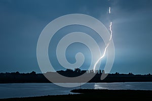 Bright lightning bolt strikes down close to a river