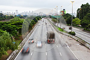 Bright lights and vehicles in transit. Sao Paulo city highway beside the river. Skyline, cars