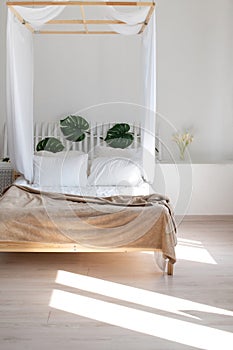 Bright loft four-poster bedroom. Wall decoration with monstera leaves