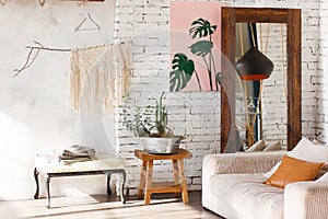 Bright loft interior with white brick walls, mirror, modern light, sofa, decor.