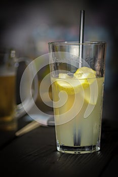 Bright lucent yellow drink lemonade with lemon slices and in darkness