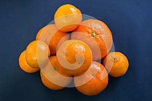 Bright mandarins are harmoniously lying on a dark blue background