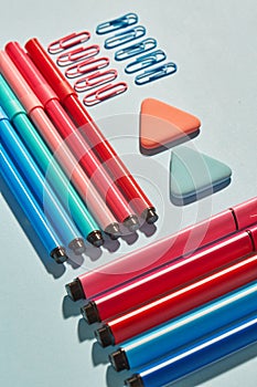 Bright markers and paper clips on a blue background