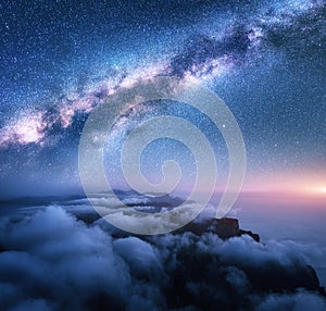 Bright Milky Way over the low clouds, mountains and sea coast