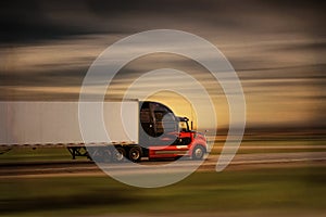 Bright modern big rig semi truck and trailer in motion on a highway