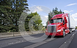 Bright modern long haul big rig semi truck with semi trailer moving on the green road