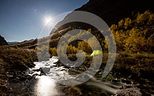 Bright moon and illuminated tent on Baduk river and valley at night