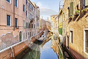 Bright morning in Venice. Narrow canal with typical Venetian boats and buildings.