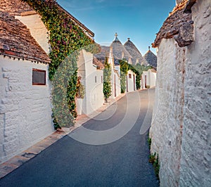 Bright morning view of empty strret with trullo trulli -  traditional Apulian dry stone hut with a conical roof