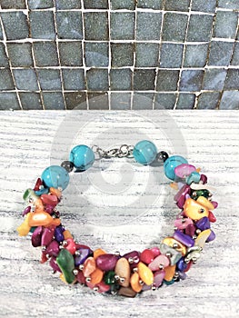 Bright multi-colored bracelet made of natural stones on a light wooden table.