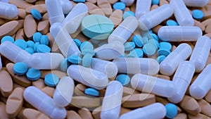 Bright multi-colored painkillers white capsules lie together. Close up rotation